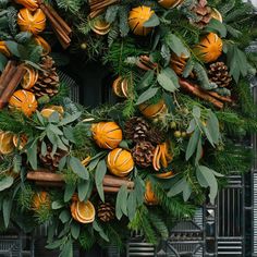 a wreath with oranges, cinnamon sticks and pine cones hanging from it's sides