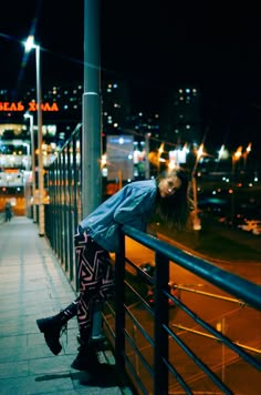 a woman leaning against a railing in the city at night