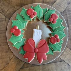 a decorated christmas wreath cookie on top of a cake plate with a lit candle in the center