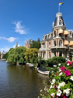 a boat is on the water in front of a large building with a rainbow flag