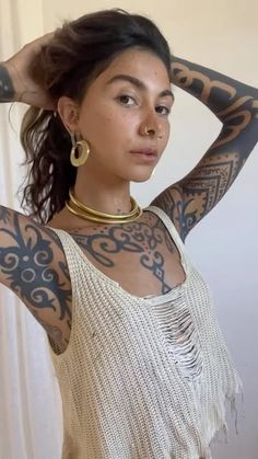 a young woman with tattoos on her arms and shoulder is posing for the camera while wearing a white top