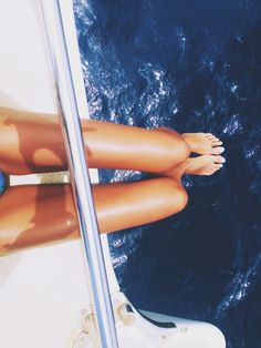 a woman's bare legs are seen from the back of a boat in the water