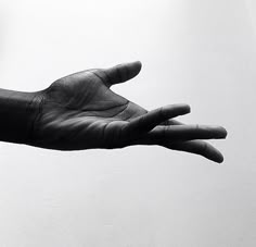 a person's hand reaching out towards the sky