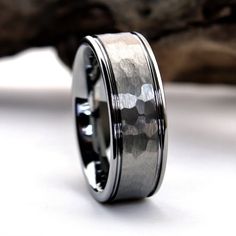 a wedding band with silver inlays sits on top of a piece of wood