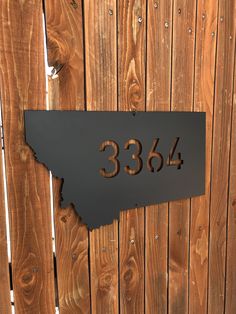 a metal plaque with the number 3504 on it in front of a wooden fence