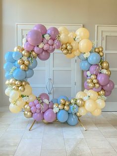 a wreath made out of balloons and flowers on a stand in front of a door