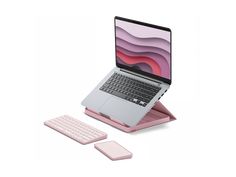 an open laptop computer sitting on top of a pink tabletop with a keyboard next to it