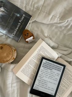 an open book sitting on top of a bed next to two stuffed animals and a tablet