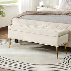 a white bench sitting on top of a rug next to a bed in a bedroom