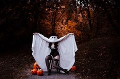 a woman dressed as a ghost sitting on a chair