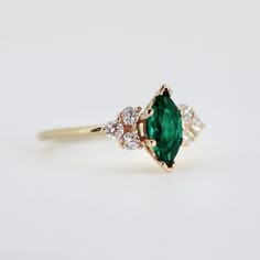 an emerald and diamond ring on a white background