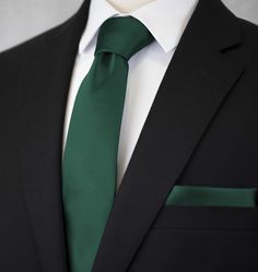 a man wearing a green tie and black suit with white shirt on his lapel