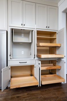 an empty kitchen with white cabinets and wooden shelves