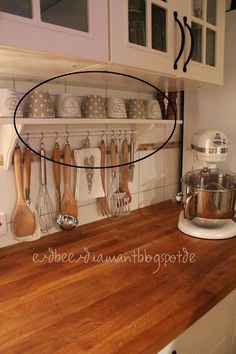 a kitchen counter with wooden utensils hanging from it's hooks and shelves