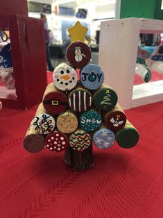 a christmas tree made out of wine corks on a red tablecloth with other items in the background