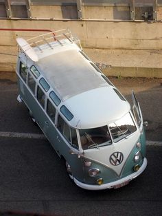 an old vw bus is parked in a parking lot next to a concrete wall