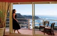 a woman standing on a balcony looking out at the ocean