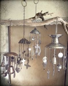 there are many bells hanging on the wall with chains attached to it and two birds perched on top of them