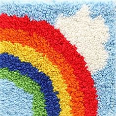 a multicolored rug with a white cloud and rainbow in the center on top