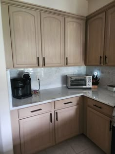 a kitchen with wooden cabinets and white counter tops is pictured in this image, there is a coffee maker on the counter