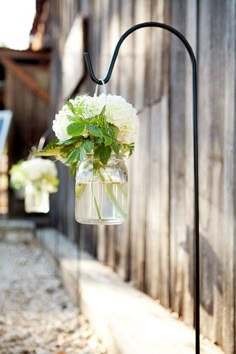 a vase with white flowers hanging from a hook