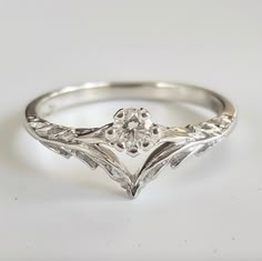 a white gold ring with an old - cut diamond in the center, set on a plain surface