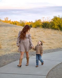 a woman holding the hand of a small child