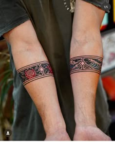 two men with matching tattoos on their arms and armbands, both holding hands together