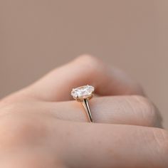 a woman's hand holding an engagement ring with a diamond in the middle, on top of her finger