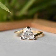 a diamond ring sitting on top of a white surface next to a green potted plant