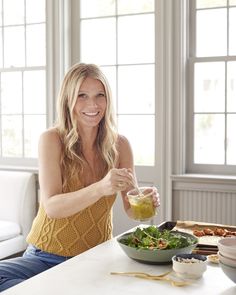 a woman sitting at a table with a bowl of salad and dressing in front of her