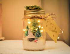 a glass jar filled with snow and christmas trees