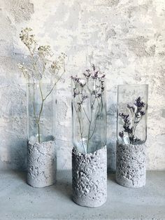 three vases with flowers in them sitting on a table