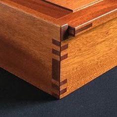 a wooden box sitting on top of a black table next to a white wall and floor