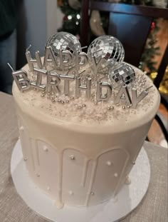 a white birthday cake with silver decorations on top