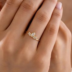 a woman's hand wearing a gold ring with two white diamonds on it and the middle finger