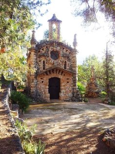 an old stone building in the middle of a forest with trees and rocks around it