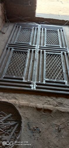 a metal grate sitting on the ground next to a brick wall and window sill