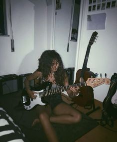 a woman sitting on the floor playing an electric guitar