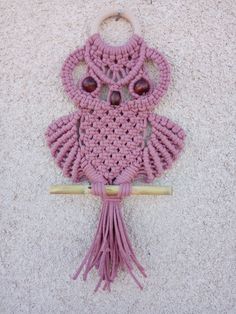 a pink crocheted owl hanging from a hook on a wall with wood beads