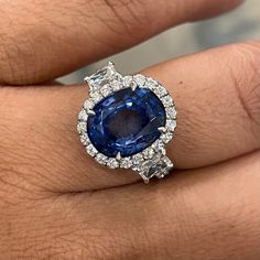 An enviable jewel, this ring sports some dazzling Diamonds & a sparkling Sapphire. Gemstones Type: Sapphire Gemstones Shape: Oval Gemstones Weight: 5.92 ctGemstones Color: Blue Diamonds Shape: Round & Radiant Side Diamonds Weight: 1.75 ct Side Diamond Color: F - G Side Diamond Clarity: VS (Very Slightly Included) Metal: 18K White Gold Metal Wt: 4.3 gms Setting: Prong & Pave Finger Size: 7 To have the ring sized, please note the desired size in Special Instructions during checkout. Luxury Gia Certified Platinum Gemstones, Luxury Gia Certified Diamond Gemstones, Luxury Gia Certified Gemstones, Luxury Brilliant Cut Sapphire Gemstones, Luxury Sapphire Gemstones With Brilliant Cut, Brilliant Cut Sapphire Diamond Gemstones, Sapphire Cushion Cut Diamond Ring, Sapphire Color Cushion Cut Diamond Ring, Luxury Diamond Cluster Ring With Gemstones