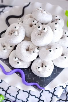 there are many white donuts with googly eyes on the top and purple ribbons around them