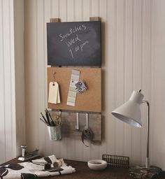 a blackboard mounted to the wall next to a lamp and some other items on a desk