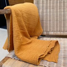 an orange blanket sitting on top of a wicker chair