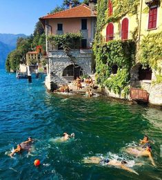 several people swimming in the water near some buildings