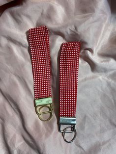 two red and white checkered straps laying on top of a pink bed sheet,