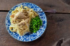 a blue and white plate topped with pasta and peas