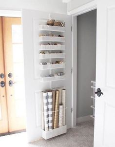 an open closet with several storage bins on the wall and two doors leading to another room