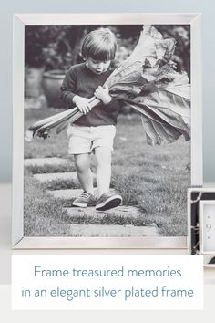 a black and white photo of a young boy holding a bunch of leaves in his hands