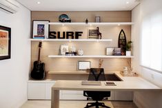 a desk with a guitar and other items on it in front of a wall mounted shelf